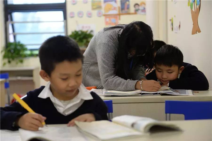 安亲托管班内，老师正在辅导学生作业